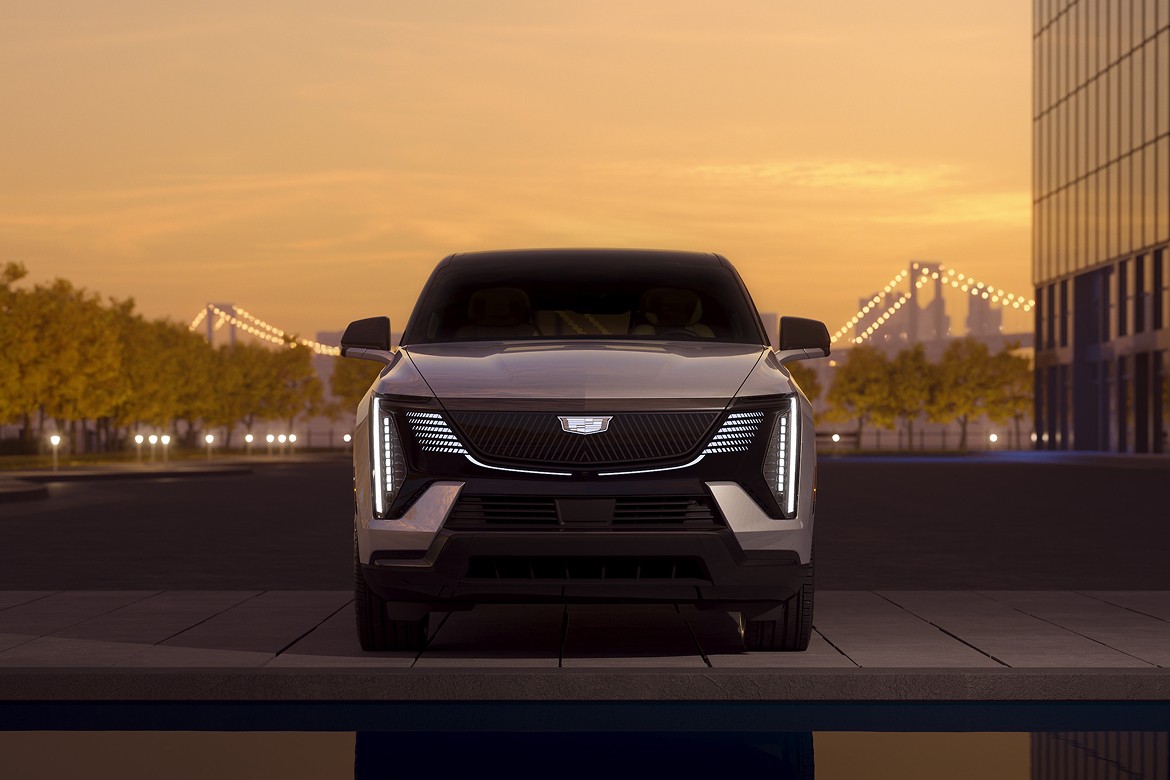 Card_Cadillac Front view of 2025 Cadillac Escalade IQ at dusk with LED lights reflected in water, set in modern cityscape.