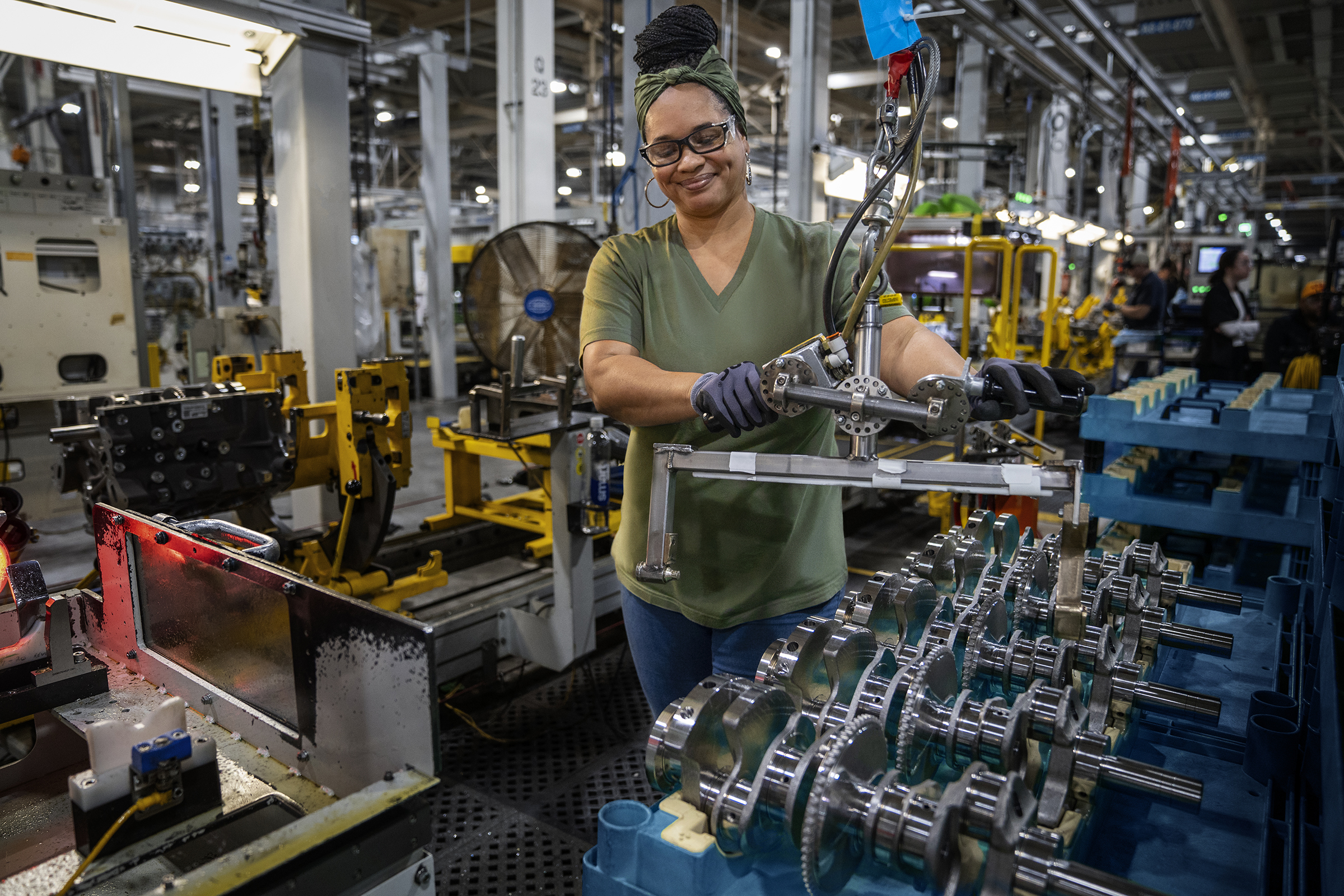 Woman in safety glasses smiling in manufacturing plant