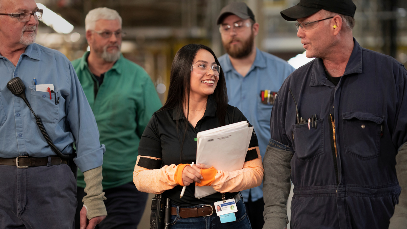 Woman in safety glasses smiling in manufacturing plant