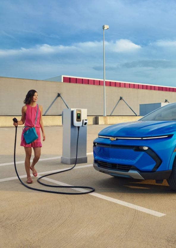 Woman Charging Her Equinox EV At Public Charging Station