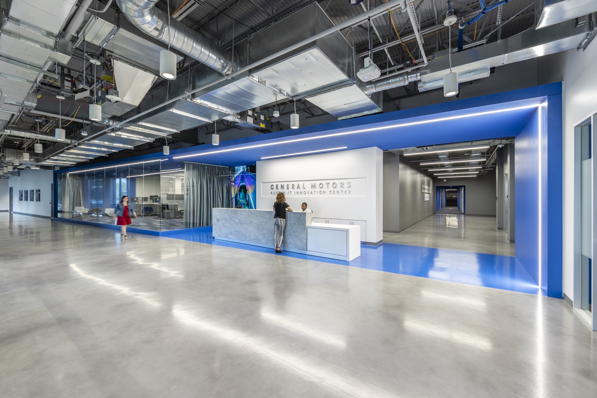 Front desk area with blue floors and outline of lights leading to long hallways at  GM Austin IT Innovation Center building