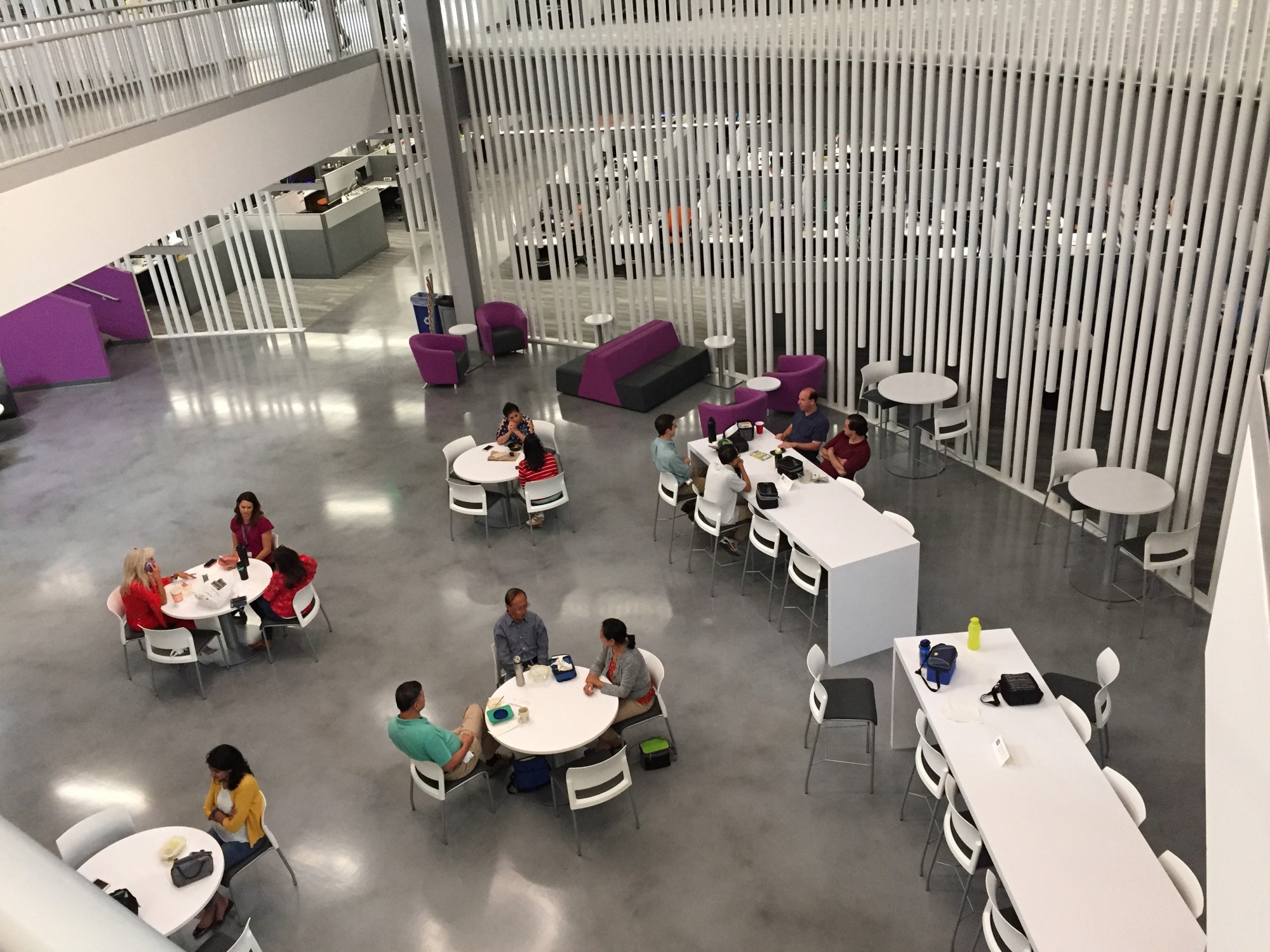 lunch break area with four round tables and two long rectangular counter tops with chairs at Austin IT Innovation Center