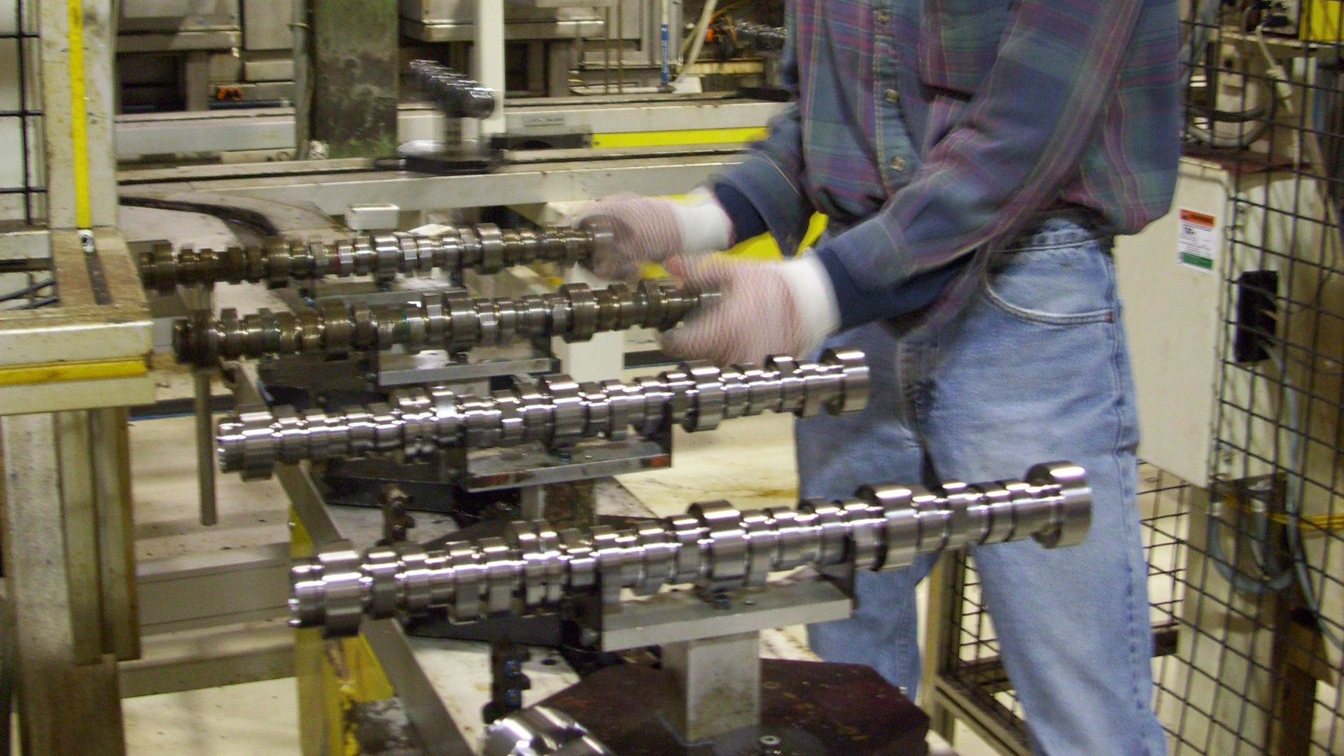 Assembly line worker works with engine component and powertrain parts