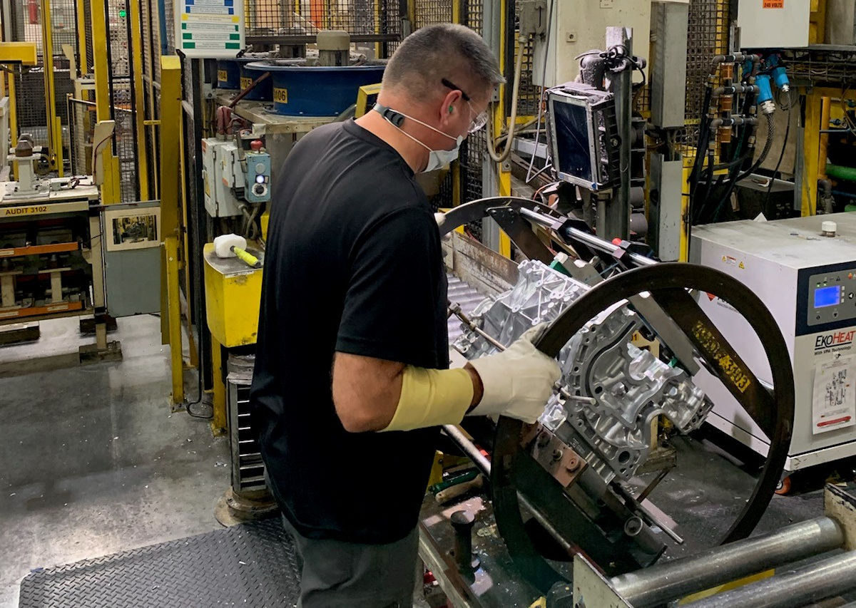 Masked and gloved production worker inspects propulsion assembly