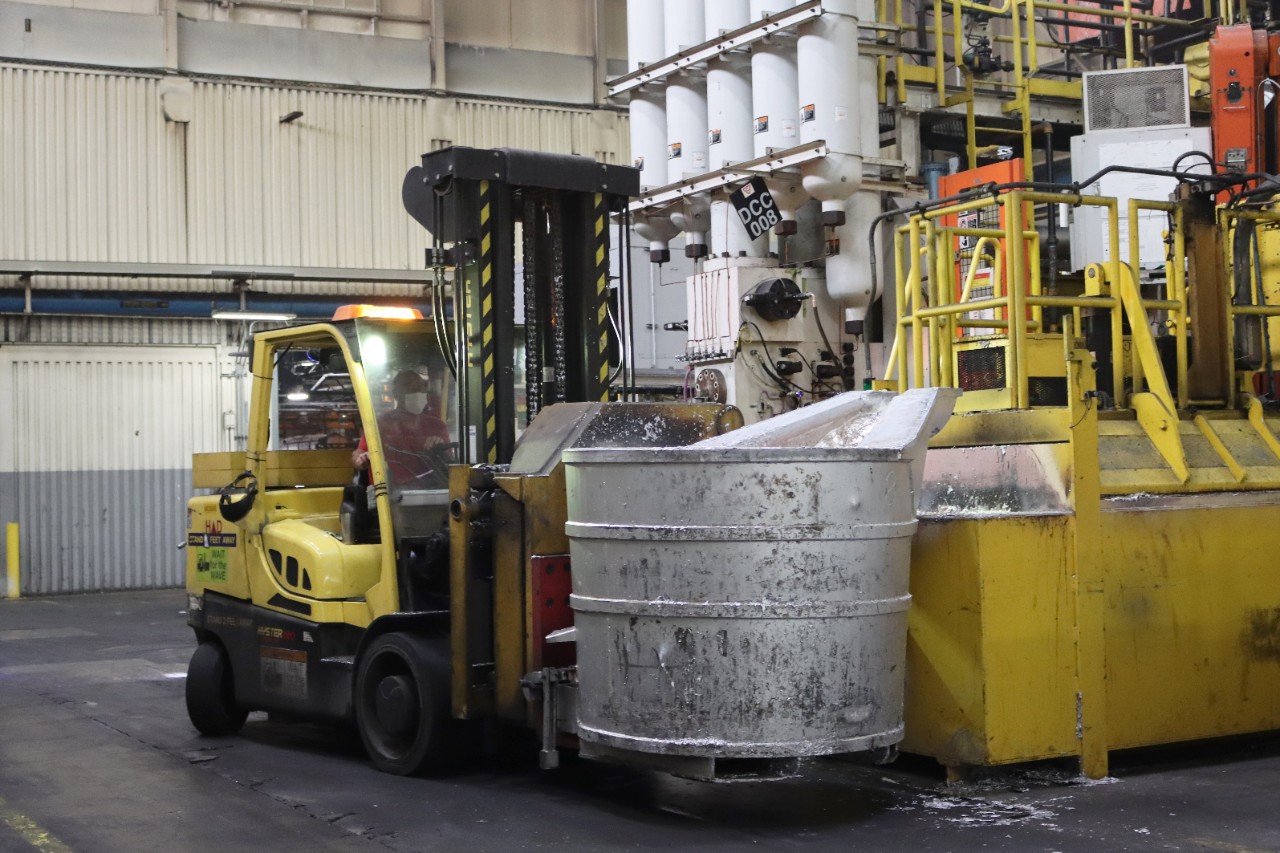 Forklift moves large metal cylinder across plant floor
