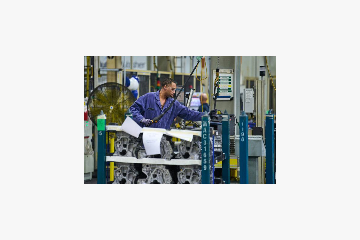 An employee pulls a rack of castings with mobile equipment.