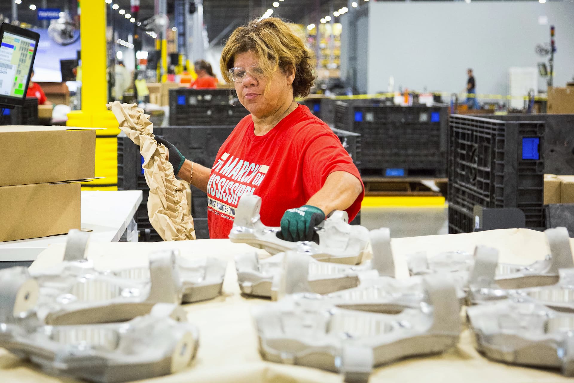 Shipping clerk prepares to wrap auto part in preparation for shipping