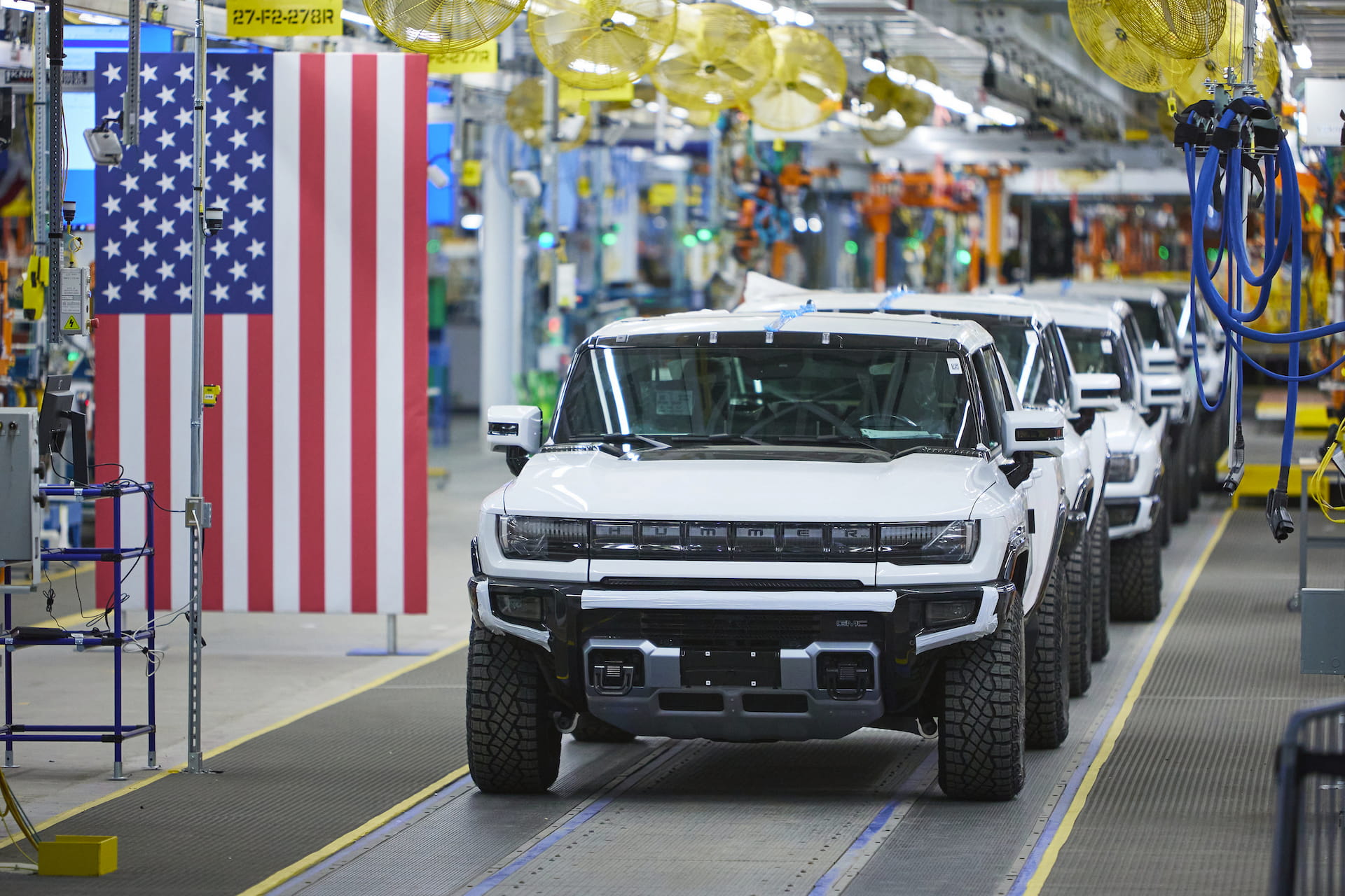 Line of Hummer EVs make their way down assembly line next to American Flag