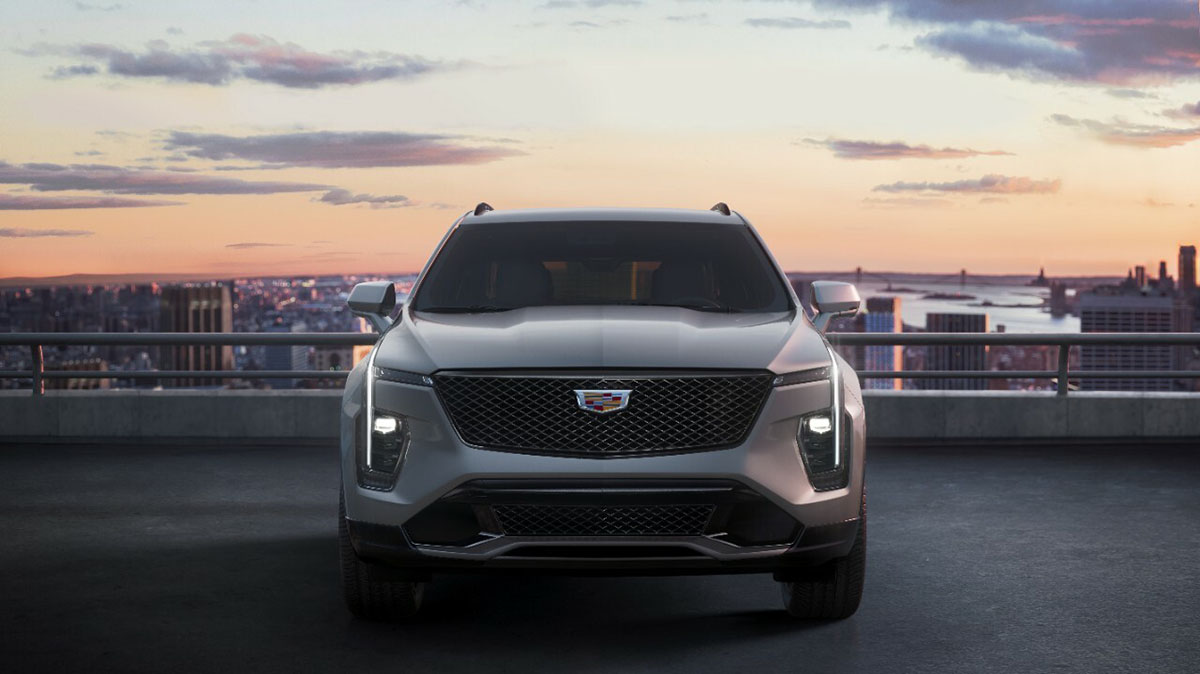 A silver Cadillac XT4 parked at the top of a parking structure overlooking a city.