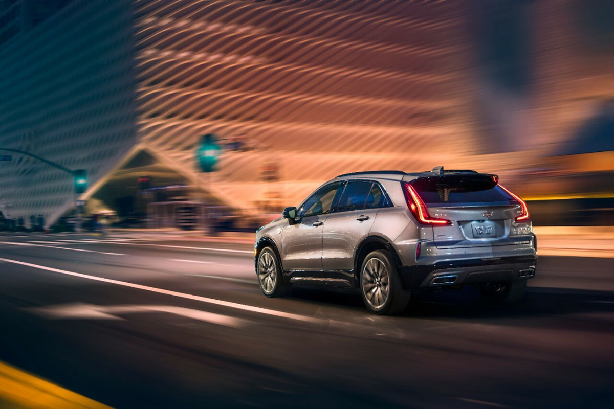 A silver Cadillac XT4 drives through a city.