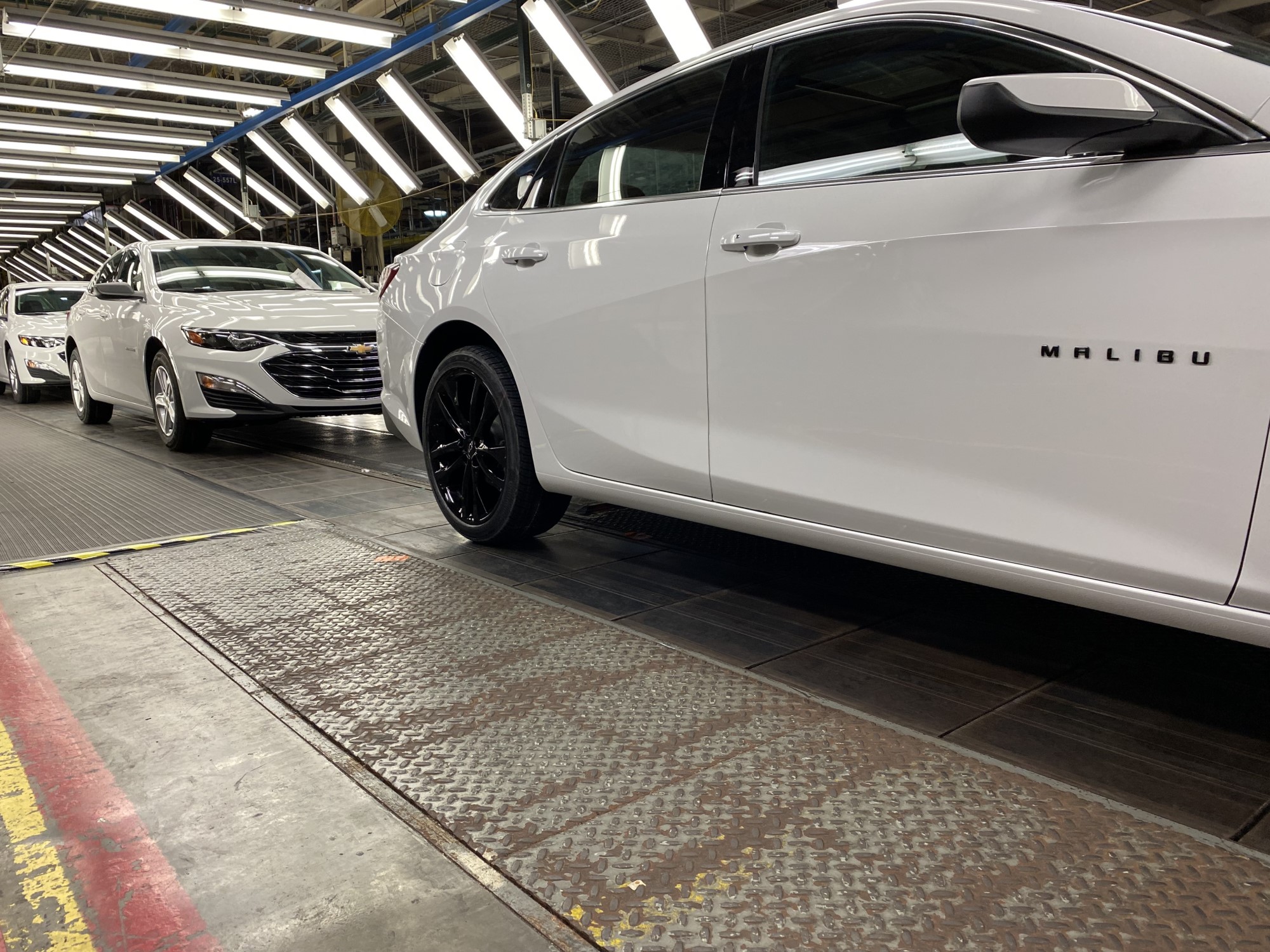 Line of white Chevy Malibus work their way down assembly line