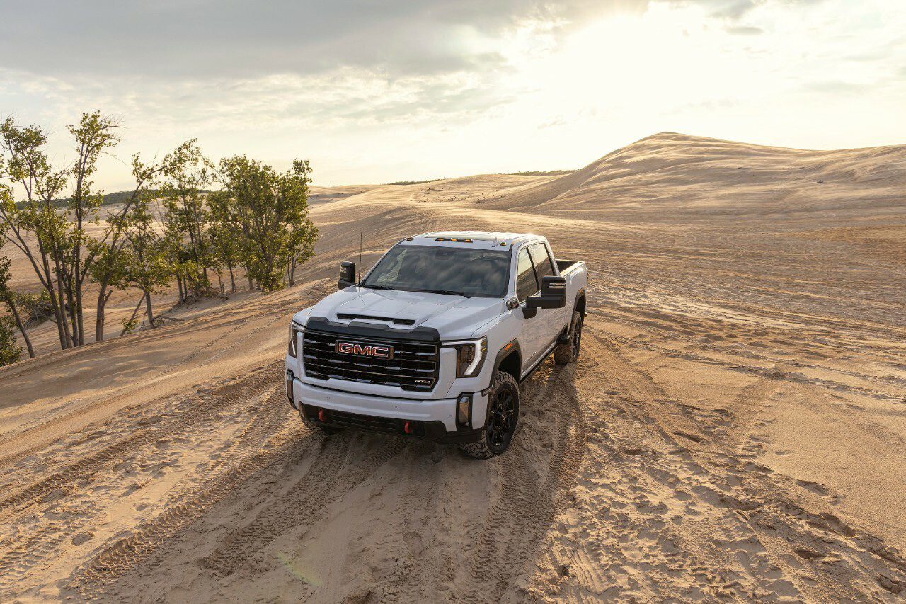 A GMC Sierra 2500 HD sits on sand in the middle of a dessert.