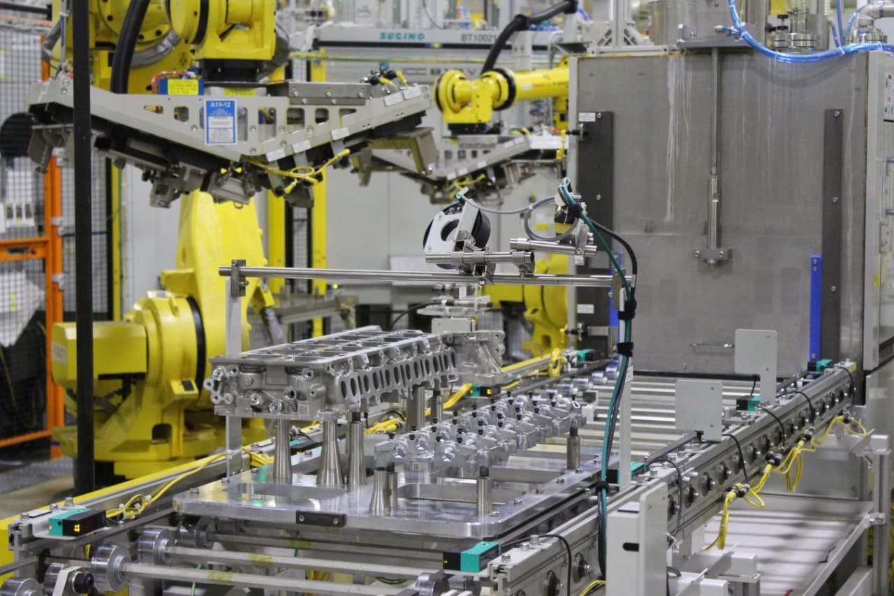 Robotic arms work on engine parts as they move down assembly line