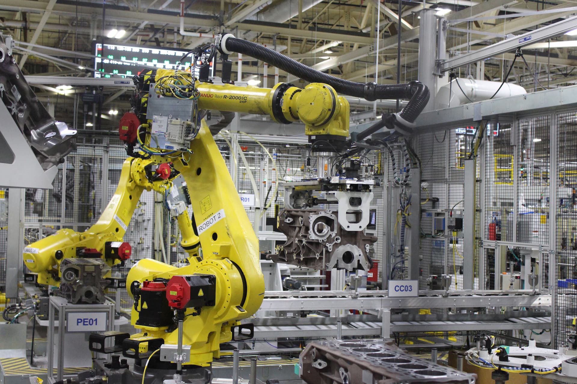 Two large robotic arms lift and move nearly completed engine
