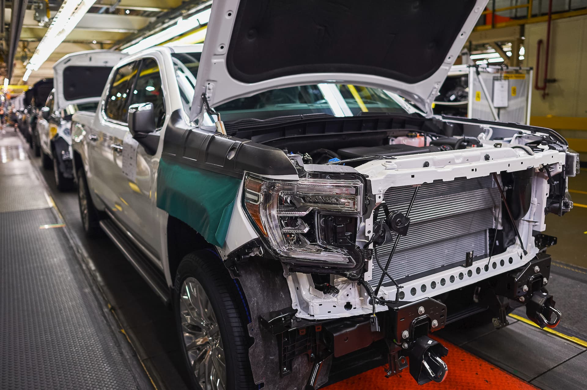 Line of trucks without front grill or bumper moves down assembly line at Fort Wayne Assembly