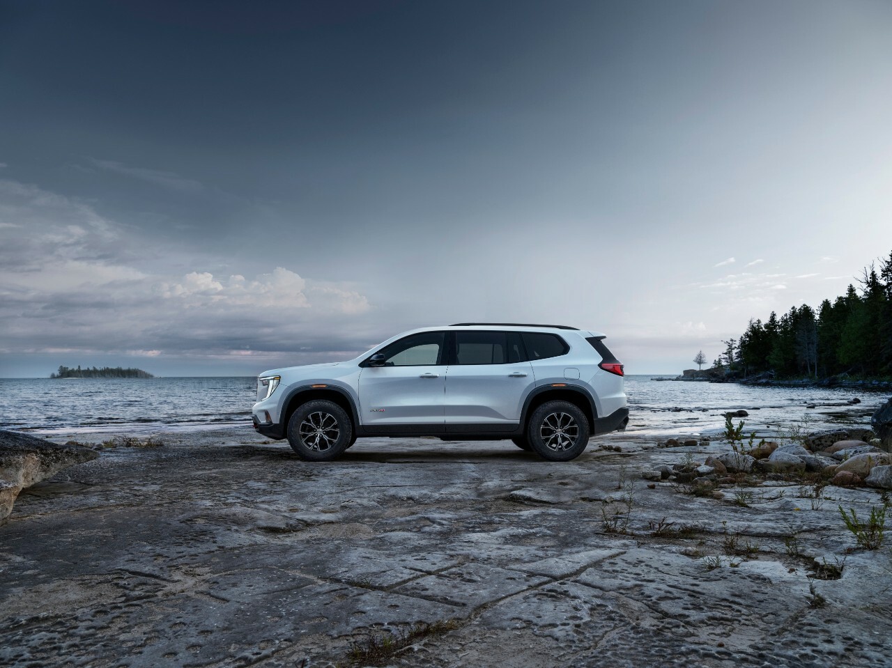 A GMC Acadia AT4 parked on a beach in a wooded area.