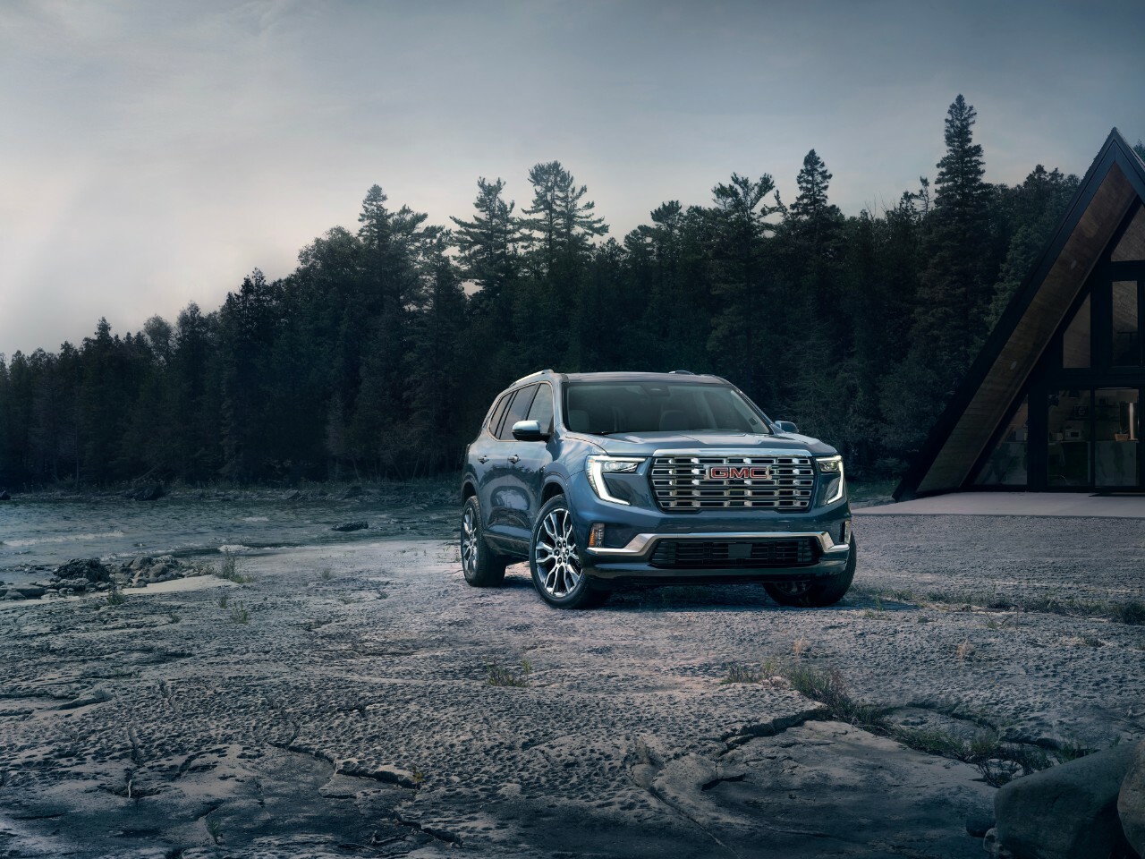 A GMC Acadia Denali parked on a beach in a wooded area.