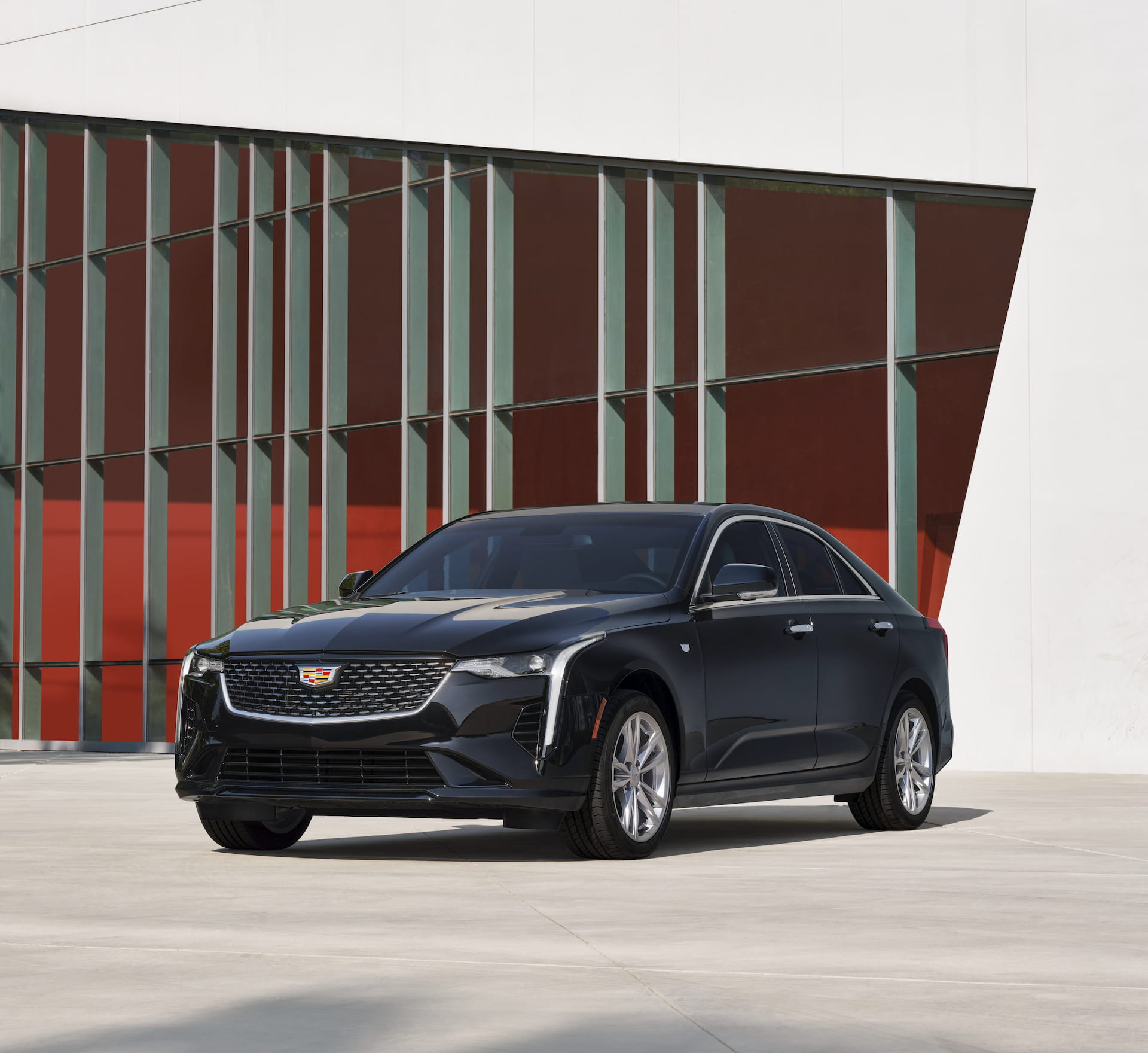 Front / side view of black 2021 Cadillac CT4 parked in front of modern industrial building