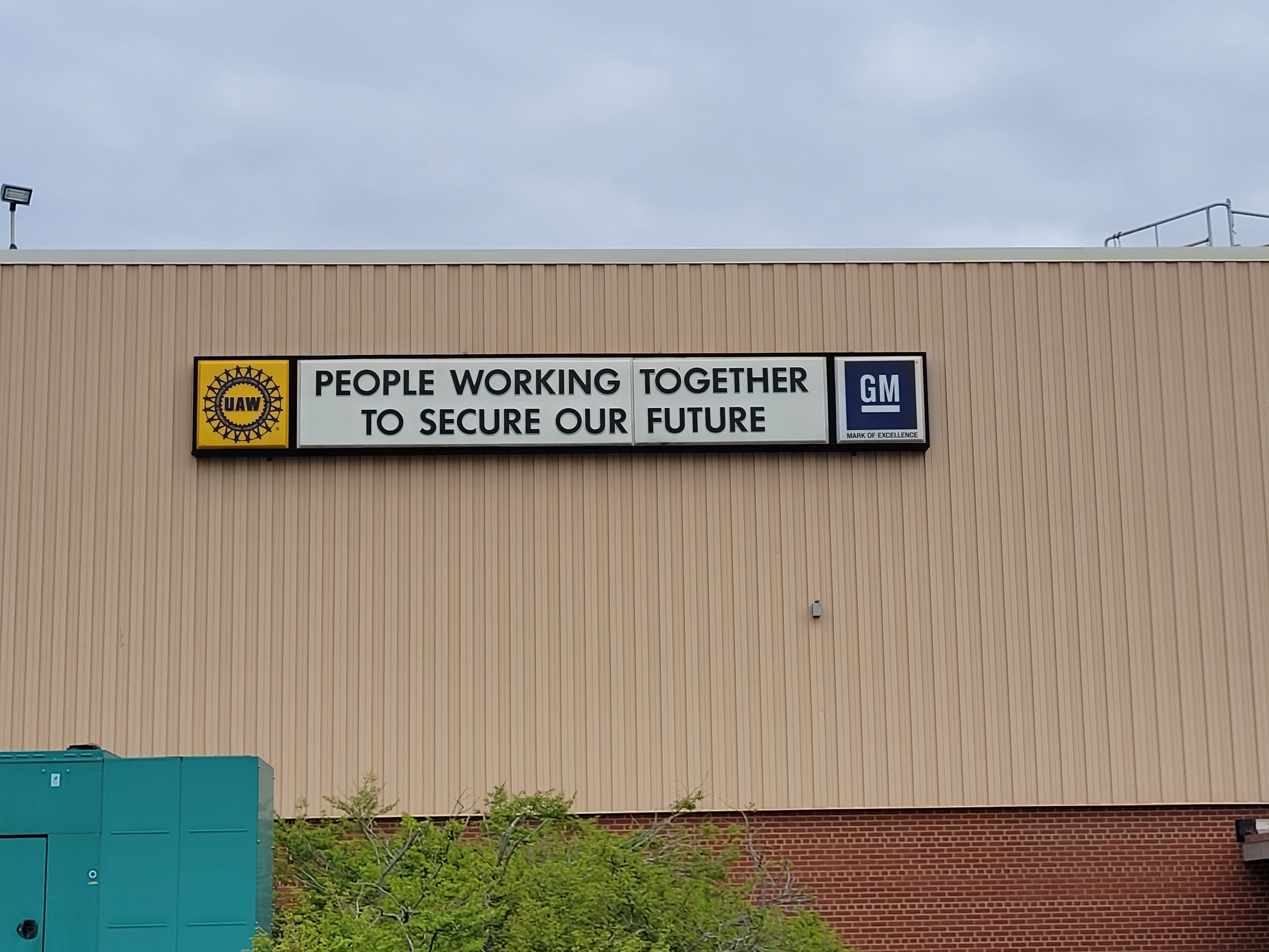 UAW and GM sign reads “People Working Together To Secure Our Future” on side of building