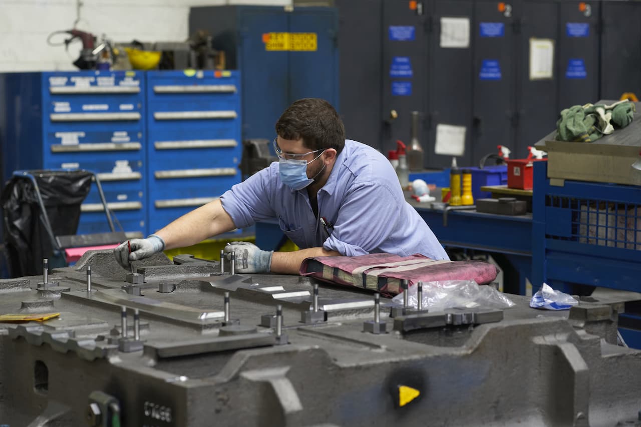 worker makes adjustments to sheet metal press