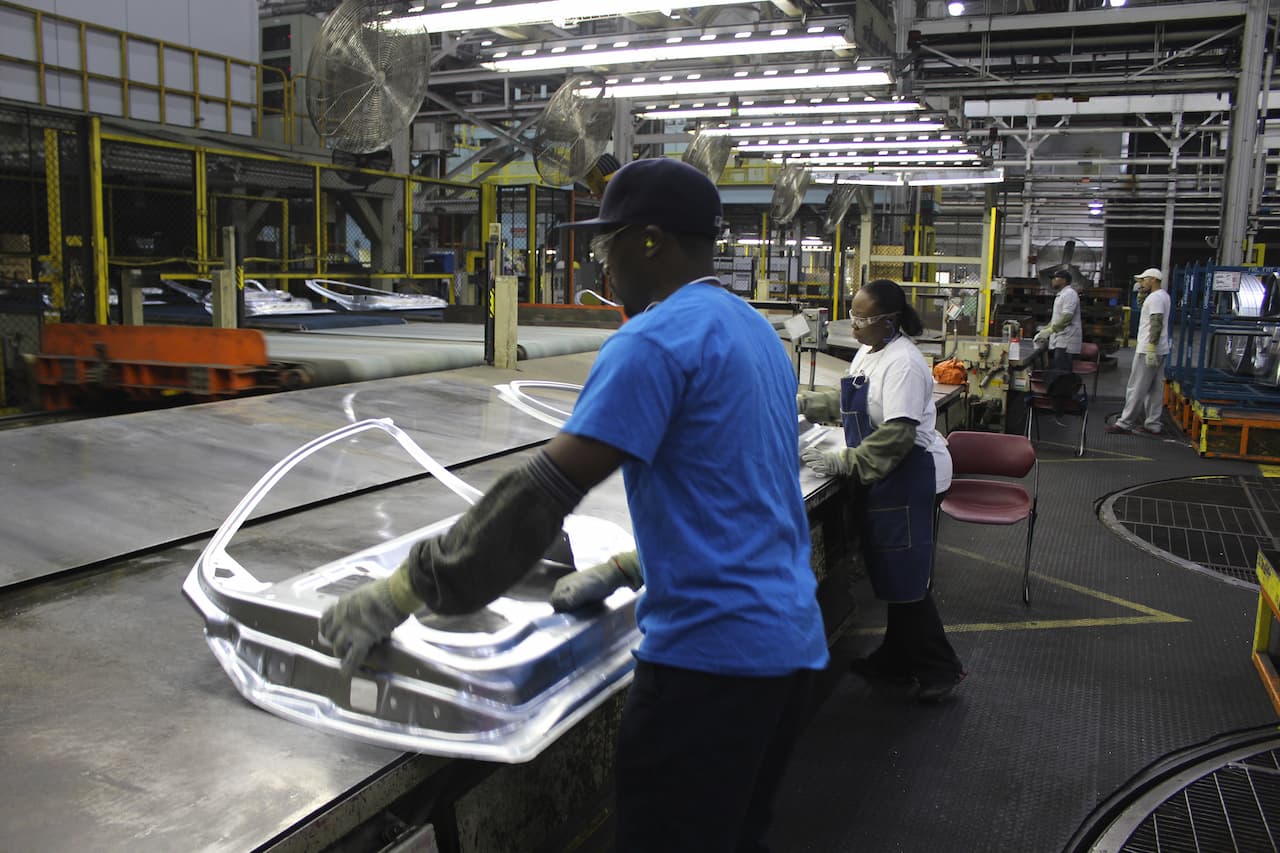 Workers on assembly line work on door assembly details
