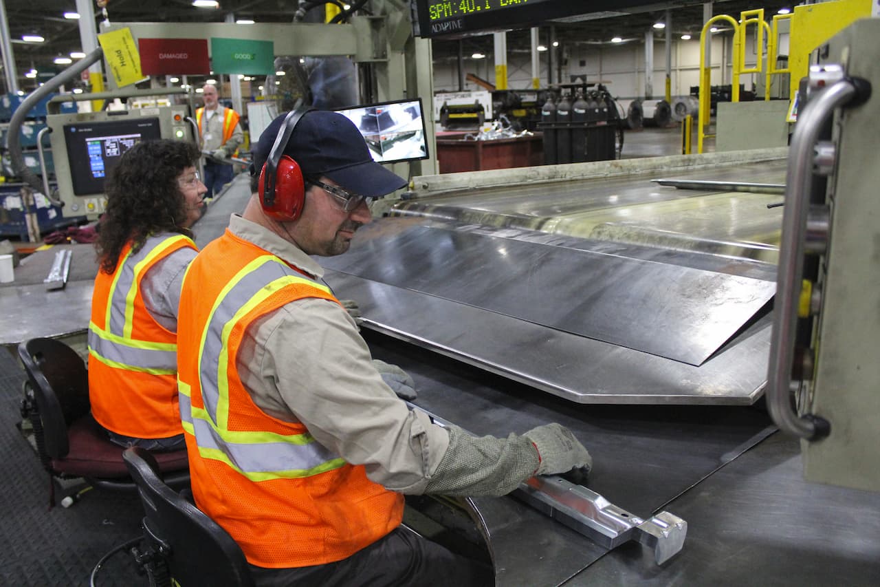 Seated parts inspection workers wait for parts to move down conveyor belt