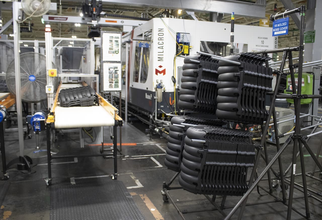 large black tubed parts sit on rack next to assembly conveyor