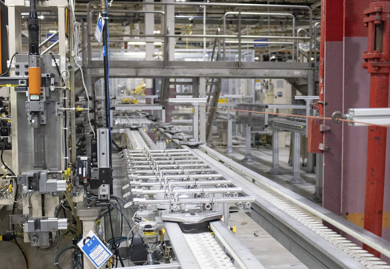 series of silver colored parts move down conveyor to next assembly station at Rochestor Operations
