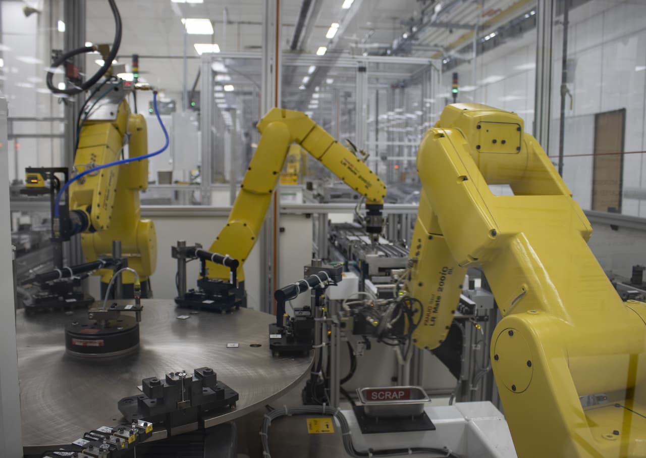 three large yellow robotic arms work in tandem to assemble parts at GM Rochestor Operations