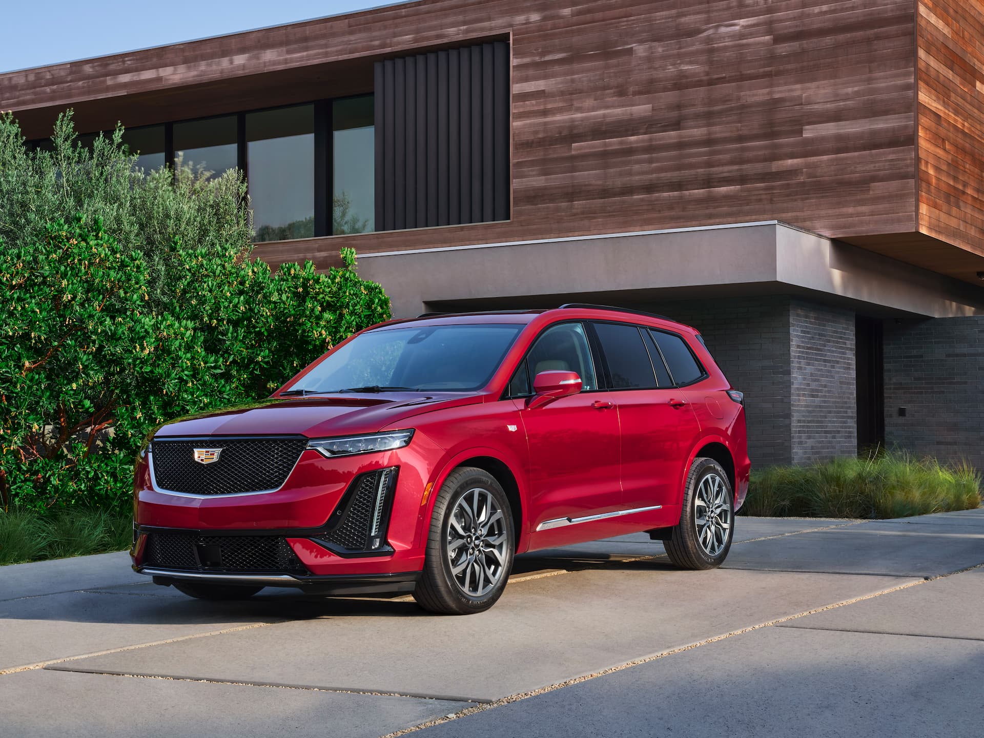 Front / side view of red 2021 Cadillac XT6 parked in driveway of modern home