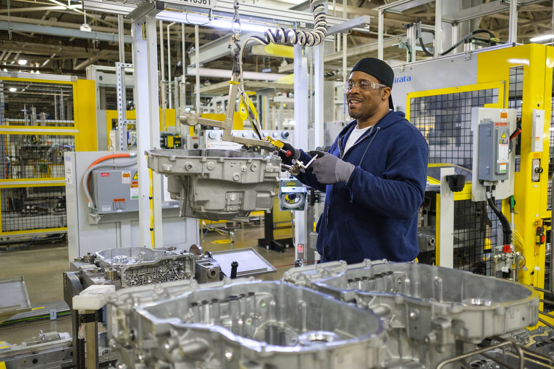 Assembly line worker works on transmission housing