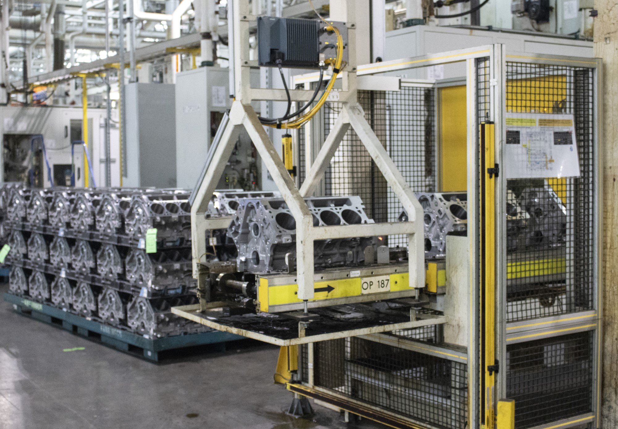 large lift moves engine blocks one by one from pallets onto caged assembly area