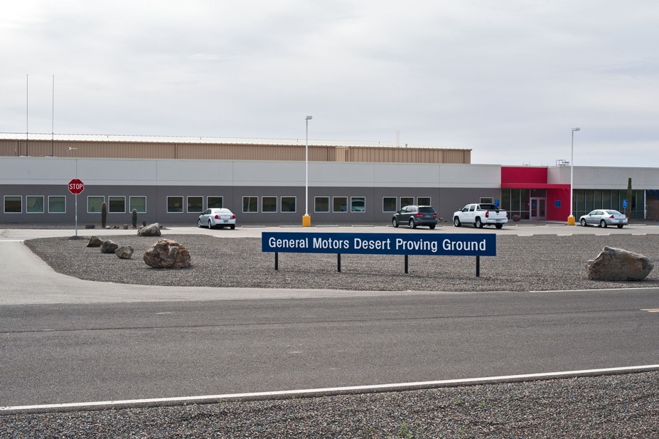 Street view of red and white engineering building at Yuma Desert Proving Ground with entry sign posted at front lot.
