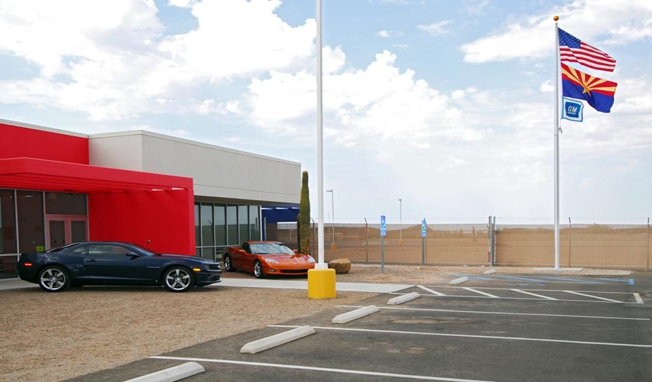 Yuma Desert Proving Ground main red and white building with gray Chevrolet Camaro SS and Red Chevrolet Corvette in front.