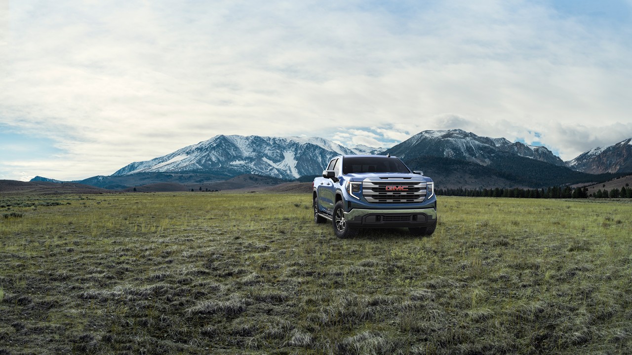 Strength Onyx Black GMC Sierra 1500 SLE parked in an open field with mountains in the background.