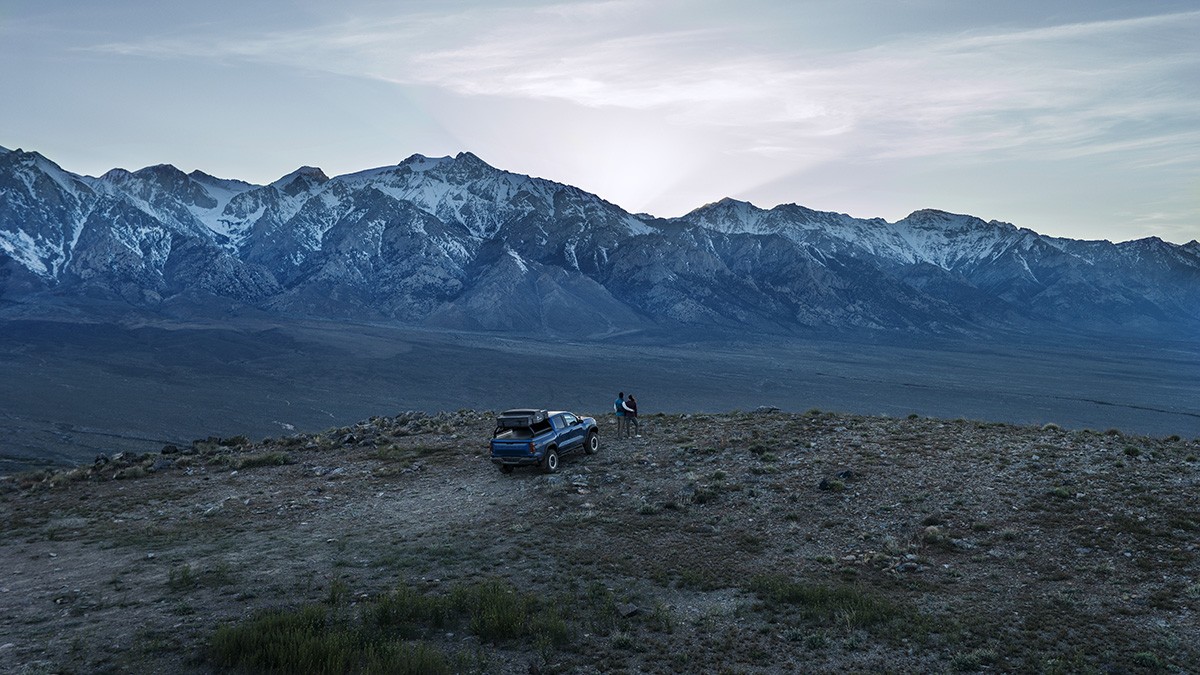 american-1 Bird's Eye View of a Couple Outlooking a Beautiful Mountain Landscape Standing Next to an Off-roading GM Vehicle