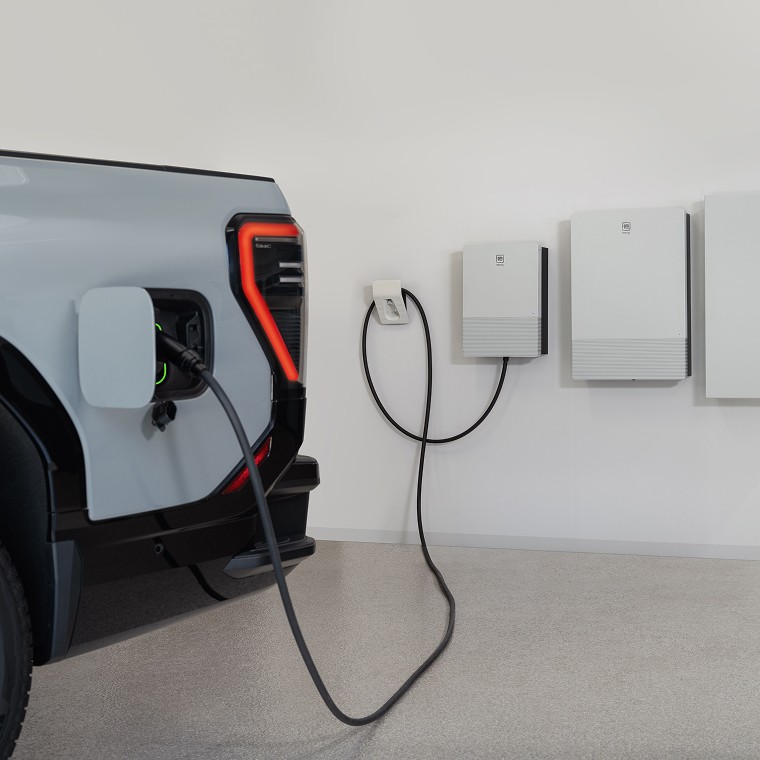 Grey electric vehicle is plugged in and charging at home with the GM Energy V2H Bundle.