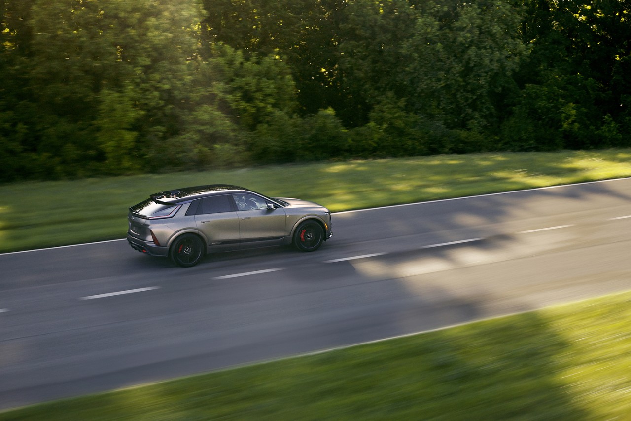 Bird’s Eye View of a GM Vehicle Driving Down a Road Lined with Trees